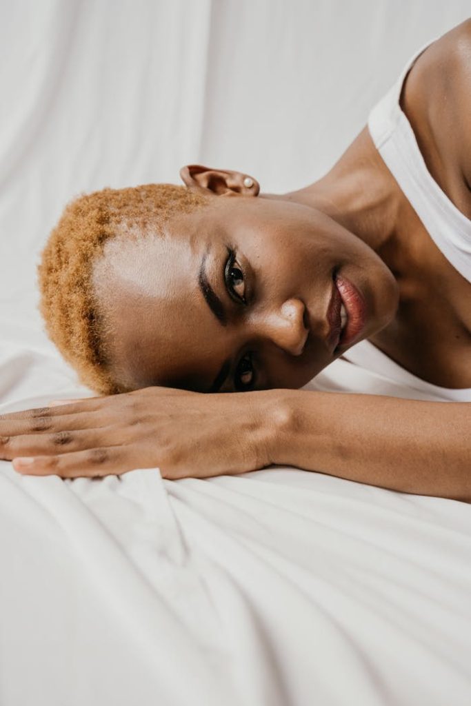 Portrait of an African American woman with short hair lying on a white surface, conveying serenity.