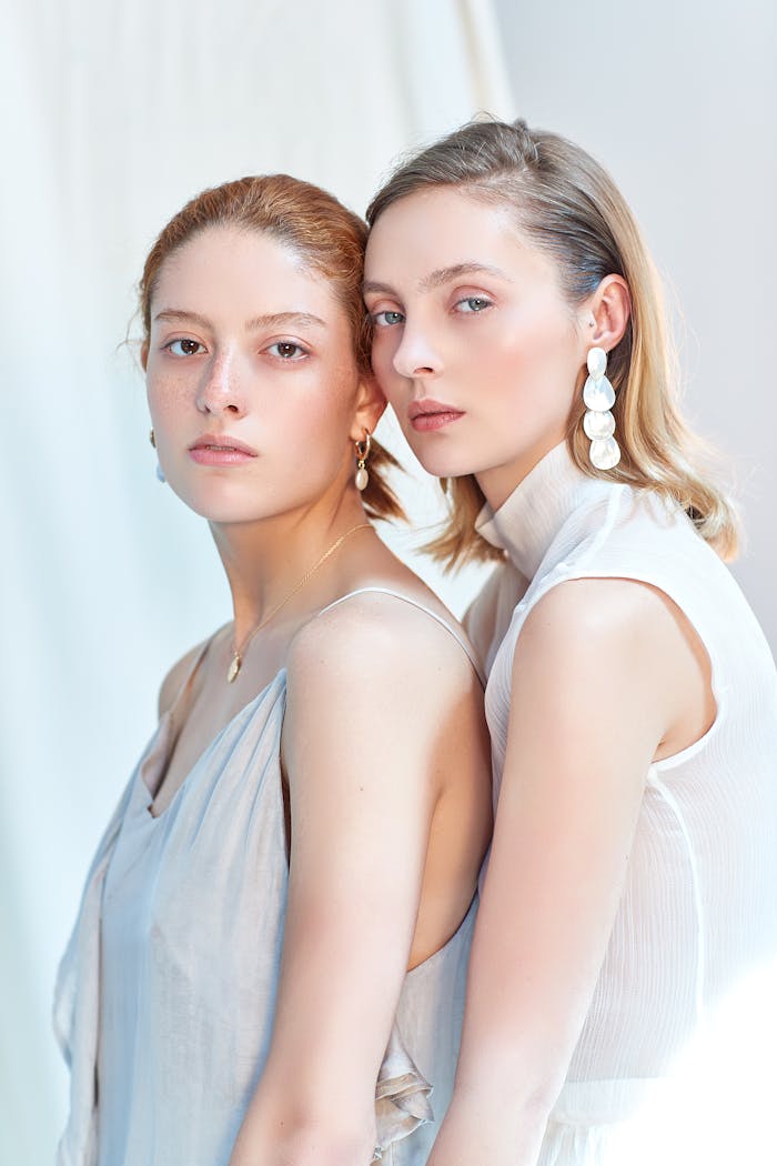 A stylish and elegant portrait of two women in a bright setting.